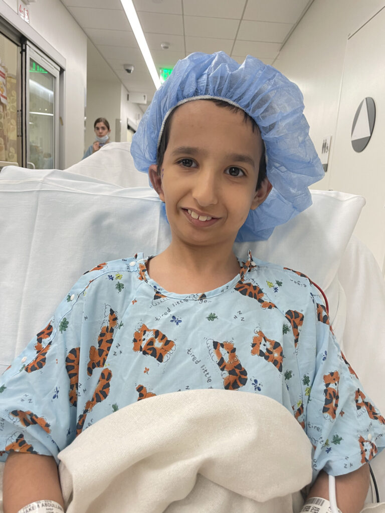 Smiling boy in a hospital gown and surgical cap before surgery