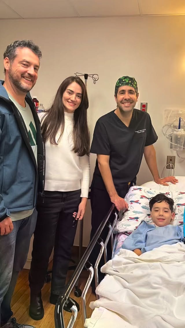 Dr. Tahiri with a young patient recovering in a hospital bed, alongside the child's parents