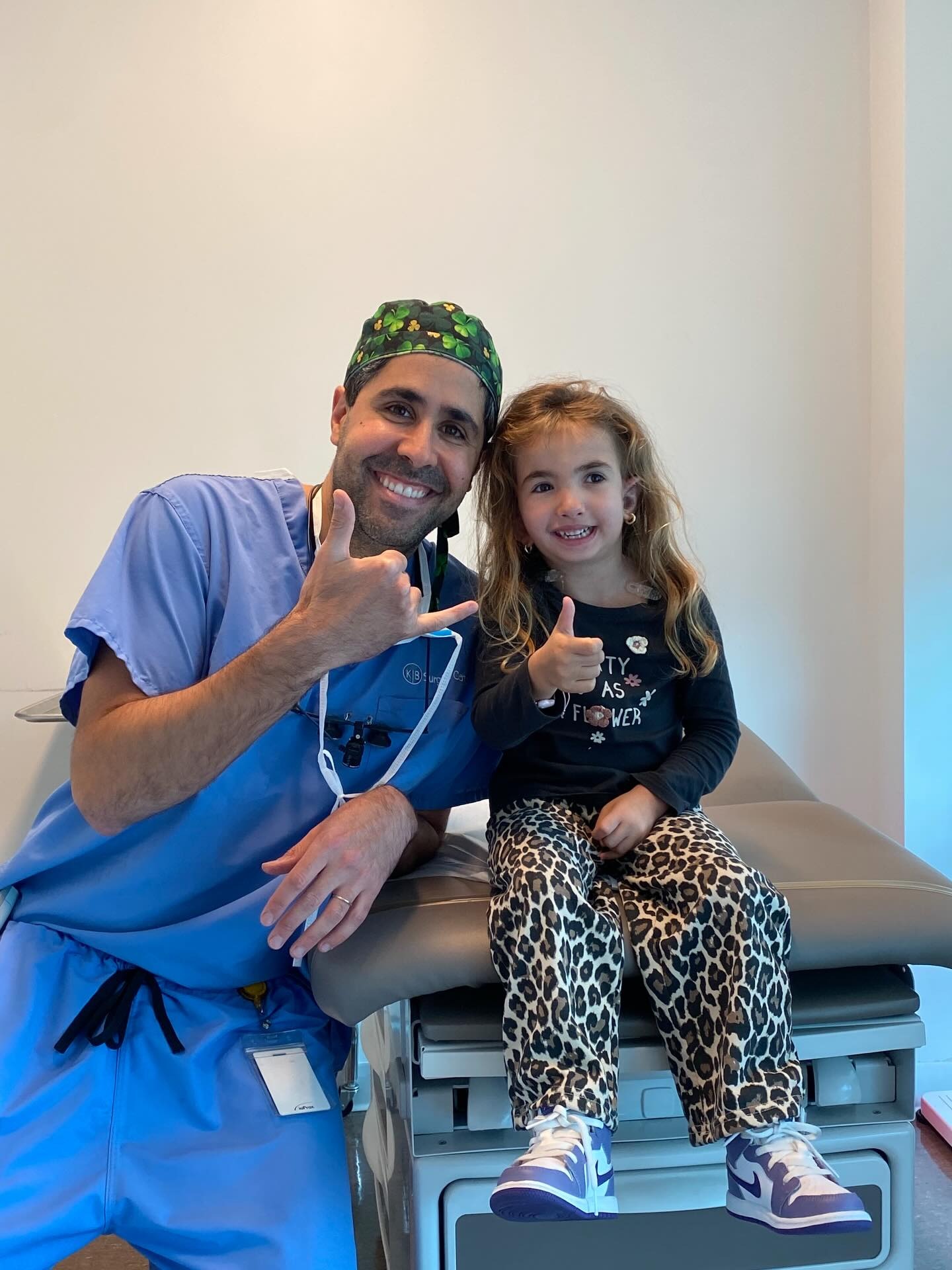 Dr. Tahiri with a young patient giving a thumbs up in the exam room