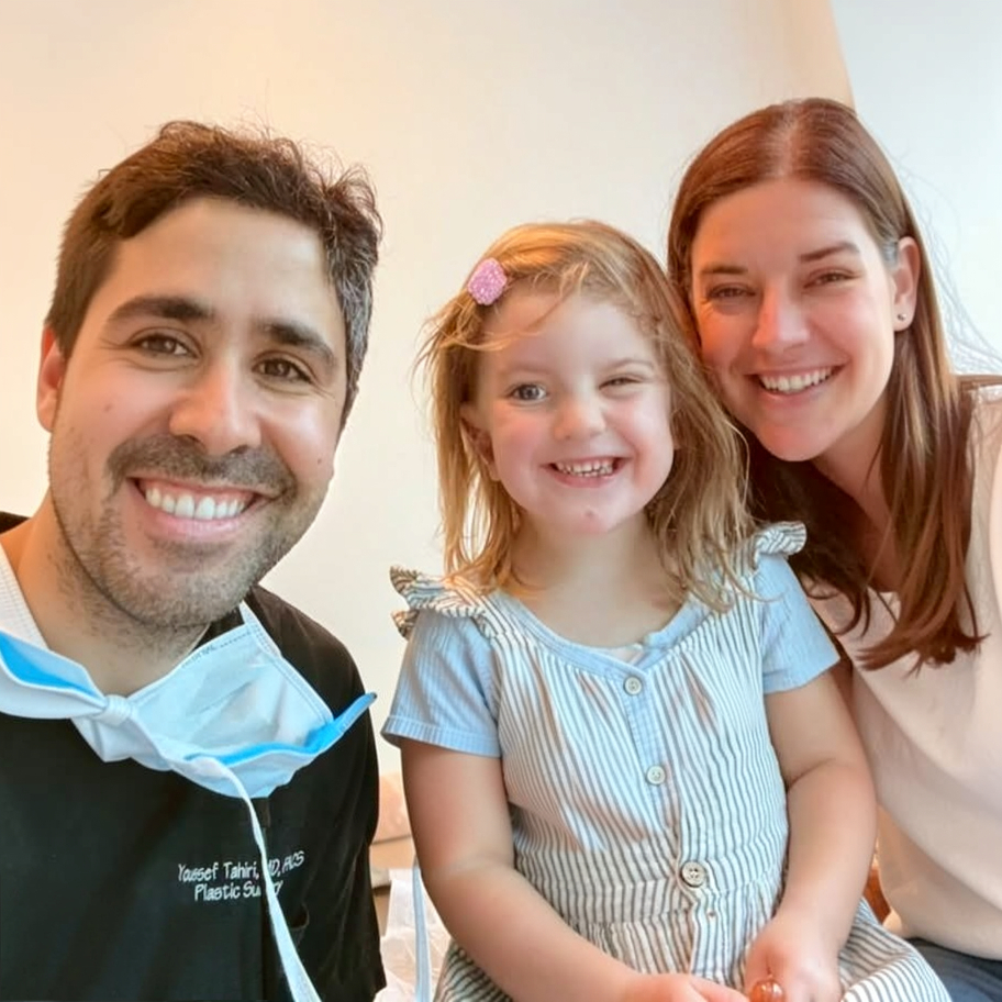 Dr. Tahiri smiling with a young patient and her mother