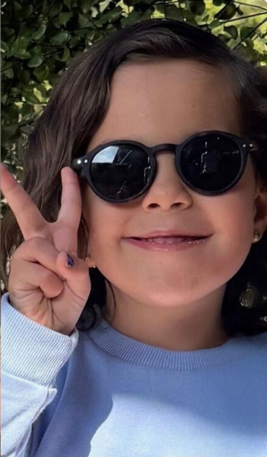 Two photos of a smiling young girl, one in a striped dress and one wearing sunglasses and making a peace sign